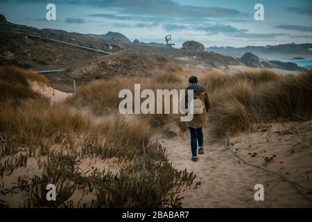 Woman walking through a beautiful dune area on the coast Stock Photo