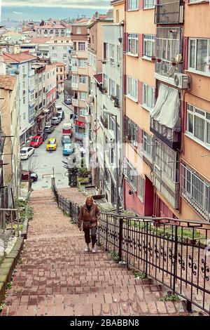 Istanbul, Turkey - February 12, 2020: A woman climbs the steep red stairs in the center of Istanbul. Stock Photo