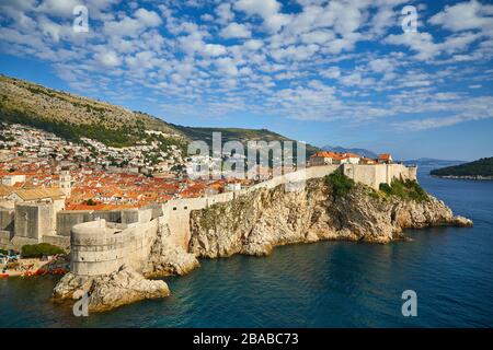 Medieval walls surround the Old Town of Dubrovnik, Croatia as it sits on the edge of land facing the Mediterranean Sea. Stock Photo