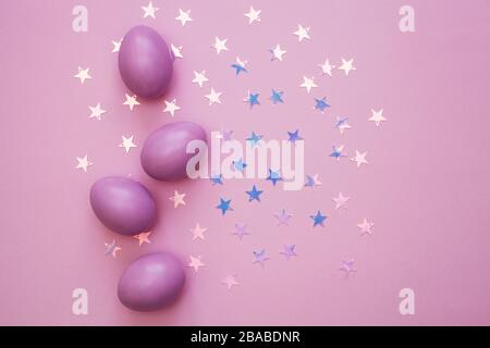 Colorful Easter eggs over pink background. Star shiny confetti Stock Photo