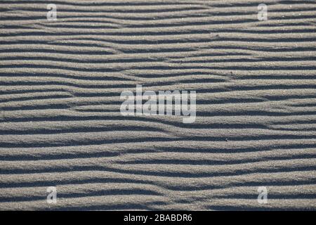 The horizontal rippled texture of sand dunes at the beach. Stock Photo