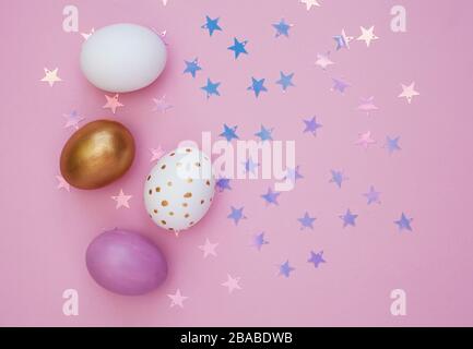 Colorful Easter eggs over pink background. Star shiny confetti Stock Photo