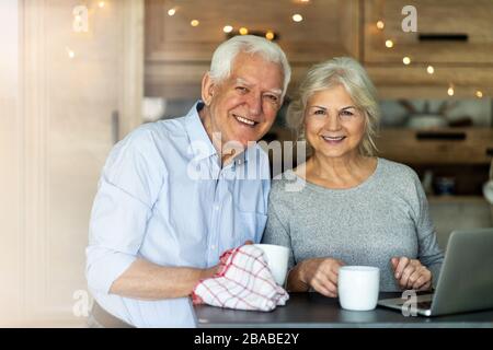 Senior couple using laptop in their kitchen Stock Photo