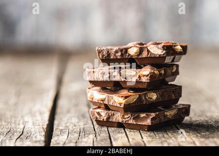 Dark nut chocolate. Broken chocolate bar on black kitchen table. Pile of chocolate. Stock Photo