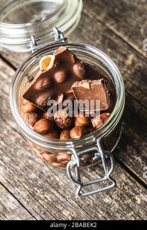 Hazelnuts and dark chocolate in jar. Broken chocolate bar and hazenuts. Stock Photo