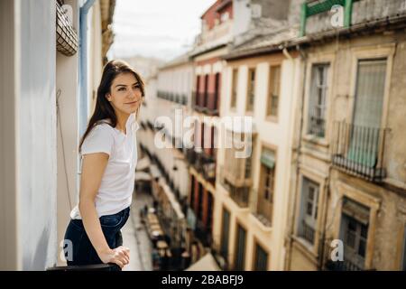 Young european woman spending free time home.Self care,staying home.Enjoying view on the balcony.Relaxing at home.Hotel room balcony view Stock Photo
