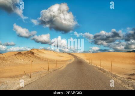 Road through sand dunes. Beautiful cloudy sky on a horizon Stock Photo