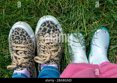 a close view of two pairs of feet a little girl and her mom with animal print and flowers on Stock Photo