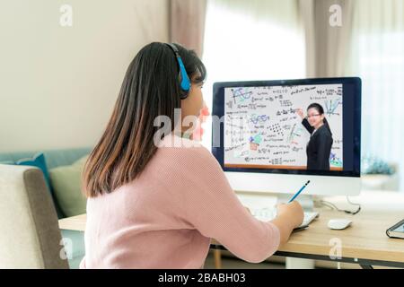 Asian woman student video conference e-learning with teacher on computer in living room at home. E-learning ,online ,education and internet social dis Stock Photo