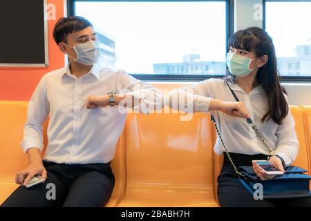 Elbow bump is new novel greeting to avoid the spread of coronavirus. Two Asian business friends meet in subway. Instead of greeting with a hug or hand