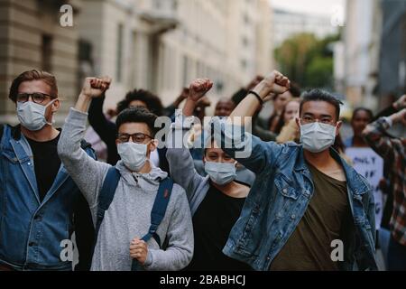 Group of activists protesting and giving slogans. Men and women marching together in a protest in the city. Stock Photo