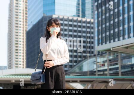 Young Asian businesswoman in white shirt going to work feeling sick with cough wears protection mask prevent PM2.5 dust, smog, air pollution and COVID Stock Photo