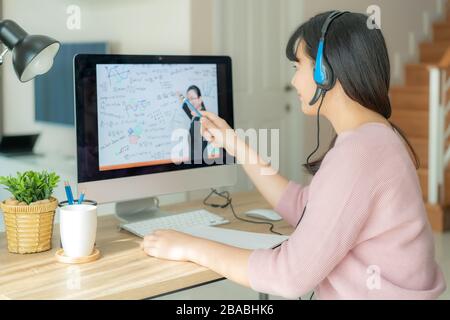 Asian woman student video conference e-learning with teacher on computer in living room at home. E-learning ,online ,education and internet social dis Stock Photo