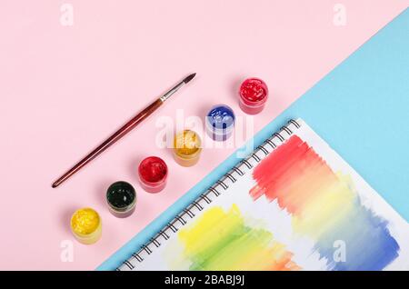 Bottles with paint and brush with colored notepad on pink background Stock Photo