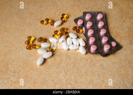 amber, pink and white capsules on a table with a pattern of sand Stock Photo