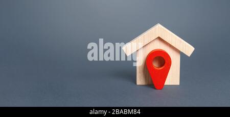 Figurine wooden house and red location pointer. The concept of the location of a building, surrounding infrastructure and the creation of a route to a Stock Photo
