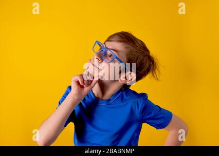 Pensive boy close-up. The cheerful boy of 9 years was thoughtful, makes a decision. The boy is thinking over a question. Stock Photo