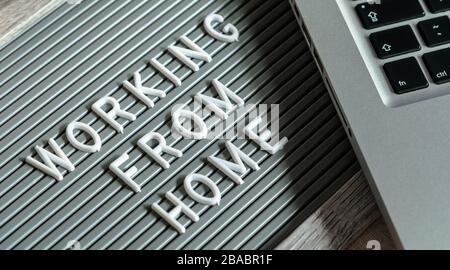Typesetting board with text "WORKING FROM HOME", laptop and pen on the desk. Working at home during quarantine concept, Covid-19 Stock Photo