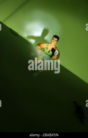 action man doll with gun seen from below in dim light Stock Photo