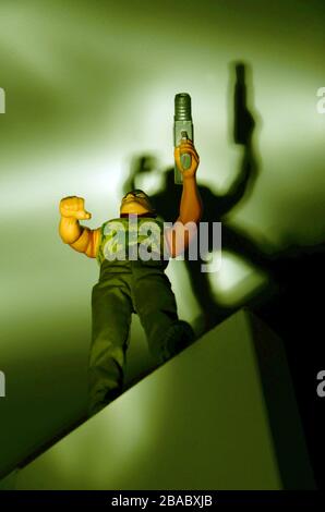 action man doll with gun seen from below in dim light Stock Photo