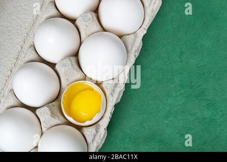 Paper Egg Tray with white eggs. chicken white eggs close up. broken chicken white egg. eggs on green background Stock Photo