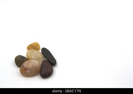 Image of some dark colored river rocks on a white background, with space for text or graphics. Stock Photo