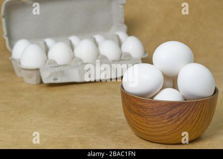 White Eggs isolated in wooden bowl on beige textured background Stock Photo