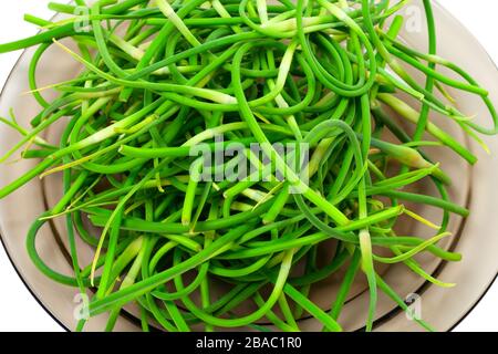 Fresh garlic scapes on plate. Close-up view. Stock Photo