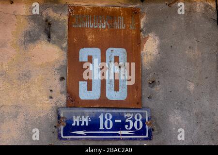 Street number 36 on a metal placard against a stucco wall, white numbers on a red and blue background Stock Photo