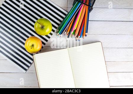 Top view of open notebook with empty pages, pencil and red apples on wooden table in office workspace Stock Photo