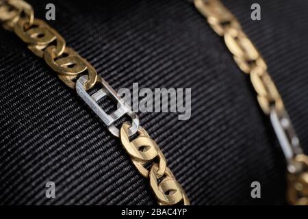 Gold and white chain on black cloth Close up. Stock Photo