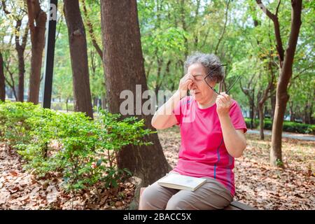 senior women have eye pain due to the reading book Stock Photo
