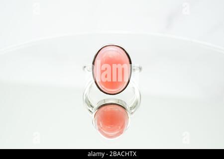 Closeup shot of a pink oval opal ring on a white surface Stock Photo