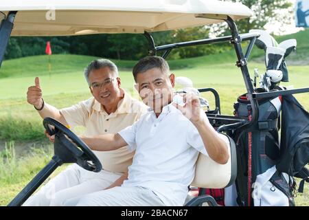 Middle-aged man sitting on a golf cart and the elderly Stock Photo