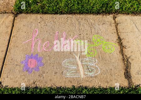 The word "Hello" written with sidewalk chalk, on gray concrete pavement background. Stock Photo