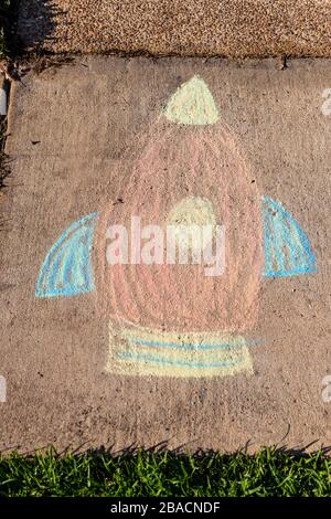 Rocketship art drawn  with sidewalk chalk, on gray concrete pavement background. Stock Photo