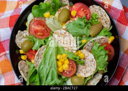 Closeup of a bowl of salad with crackers and vegetables on a napkin on the table Stock Photo