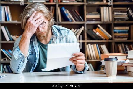 Frustrated depressed desperate young businessman read letter. Stock Photo