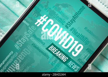 Breaking News, Coronavirus or Covid-19 outbreak background concept. Mockup mobile phone Covid19 News on light blue facial masks. Flat lay top view. Stock Photo