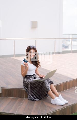 Young Asian woman using laptop to buy online with credit card. Stock Photo