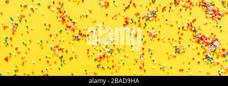 Multicolored candy dragees on yellow background. Top view. Flat lay. Festive, birthday celebration, Easter composition, greeting card. Stock Photo