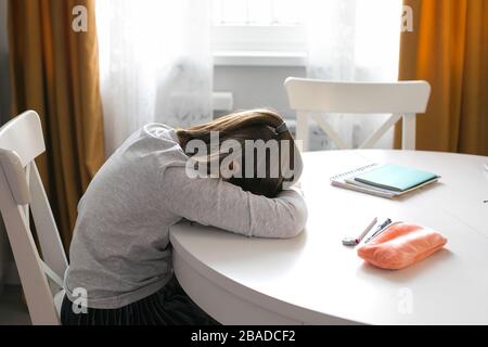 Pretty cute schoolgirl 7-8 years old sleeping on table. Home school, online education, home education, quarantine, coronavirus concept Stock Photo