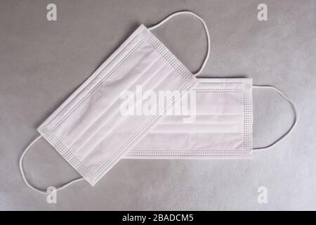 two protective medical face masks for acute respiratory viral disease 2019-nCoV on a silver background top view. air pollution coravirus. Stock Photo