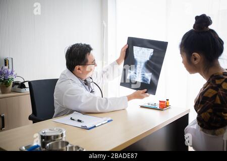 The doctor is explaining about the brain X-ray results to a female patient in his office at Hospitals Stock Photo