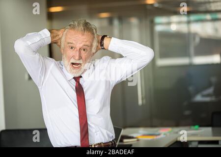 Happy handsome businessman standing and smiling in office Stock Photo