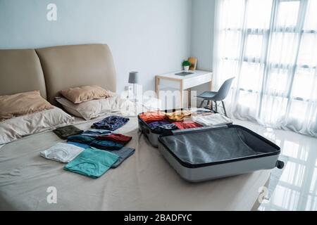 suitcase with lots of clothes on the bed, preparation before traveling Stock Photo