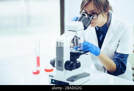 Young scientist looking through a microscope in a laboratory. Young scientist doing some research. Stock Photo