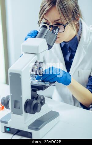 Young scientist looking through a microscope in a laboratory. Young scientist doing some research. Stock Photo