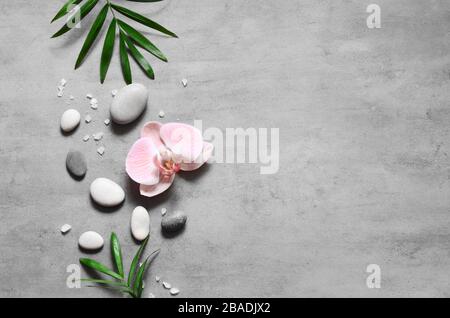 Spa concept on stone background, palm leaves, flower and zen, grey stones, top view, copy space Stock Photo