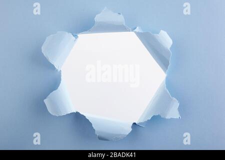 Abstract advertising with blue torn hole paper on white background for concept design. Torn paper sheet. Stock Photo